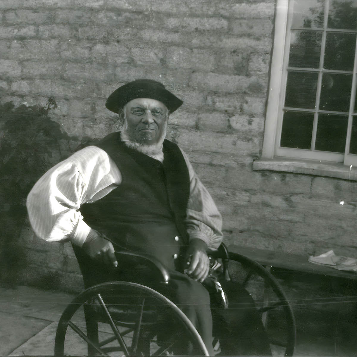 Man in wheelchair, smartly dressed in waistcoat and hat