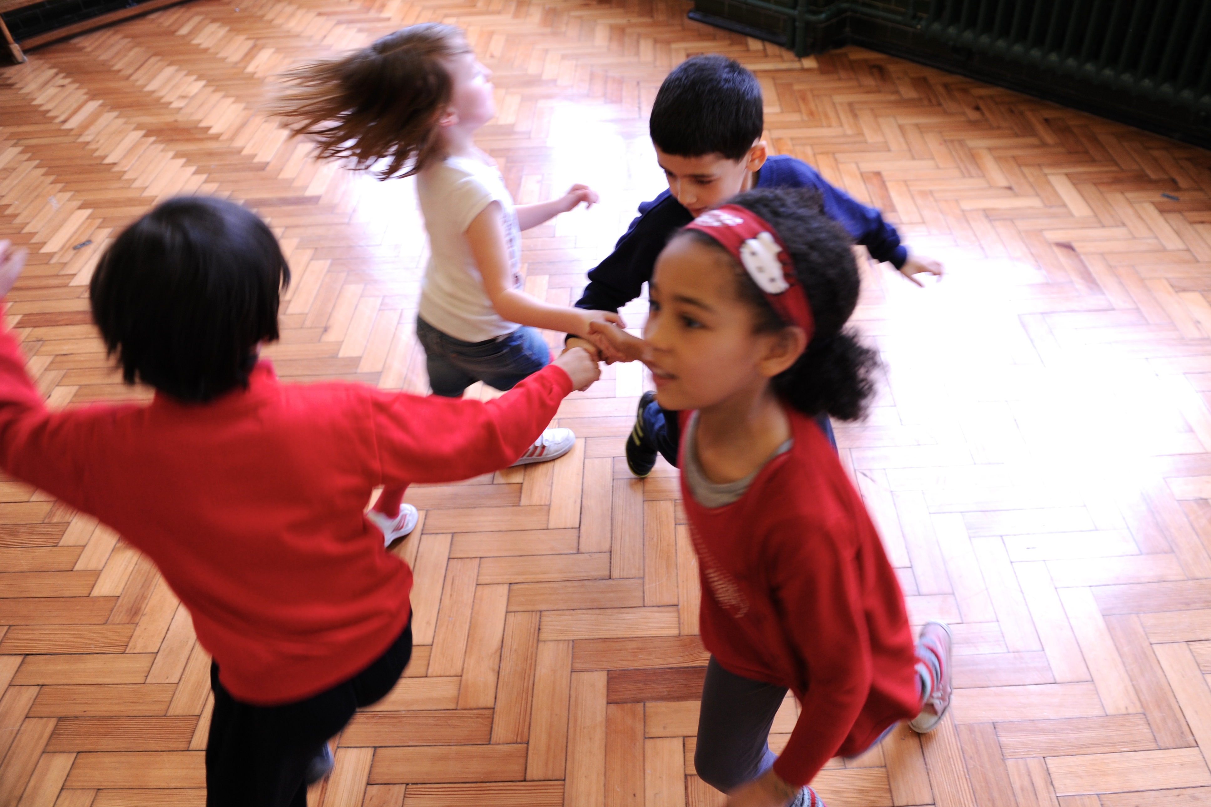 Four children dancing in a circle.