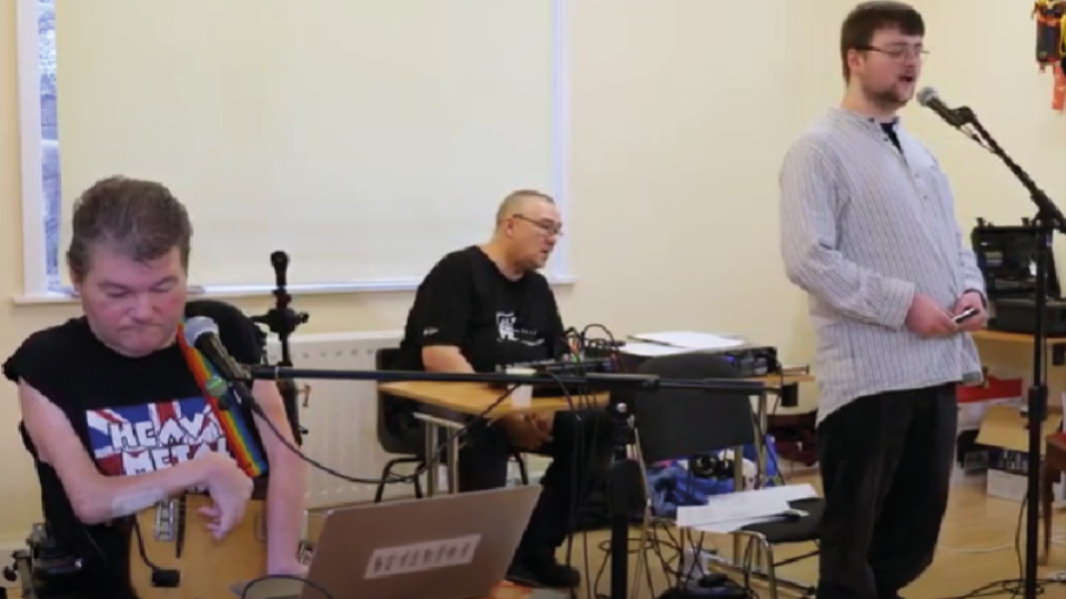 video still: Oliver Cross (harmonica and vocals) and John Kelly (kellycaster and vocals) presenting their research project at Cecil Sharp House