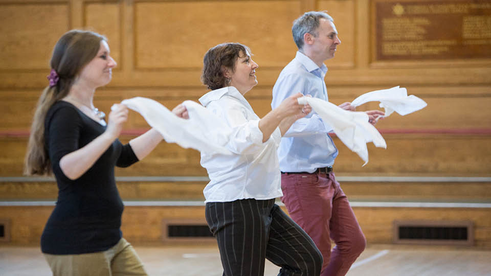 two women and one man dancing with white hankies