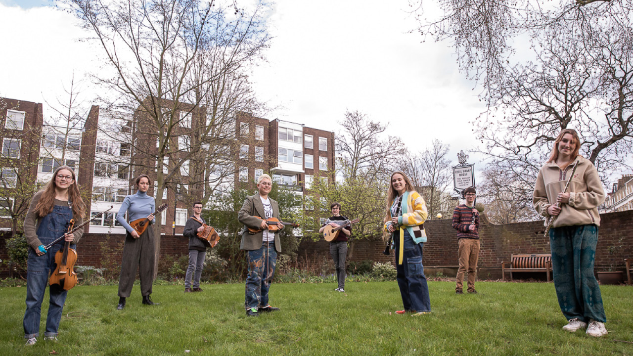 Young musicians with instruments, standing in enclosed garden at Cecil Sharp House