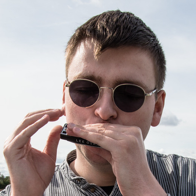 man playing harmonica, wearing dark glasses