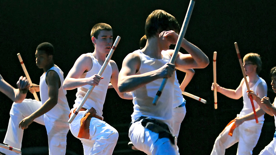 male dancers dressed all in white with blackout background, holding morris sticks